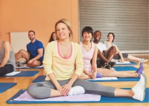 Personnes souriantes en cours de relaxation sur tapis, dans une salle lumineuse